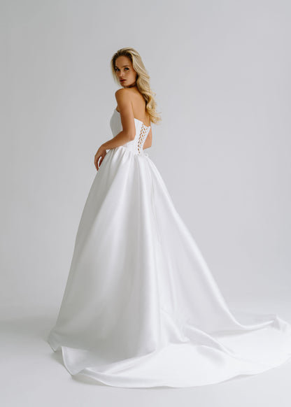 Back view of a satin wedding dress with a lace-up corset back and a train