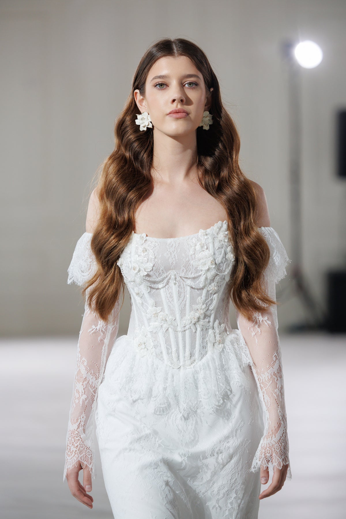 Model in a lace wedding dress with a corset bodice and sheer lace sleeves