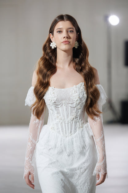 Model in a lace wedding dress with a corset bodice and sheer lace sleeves