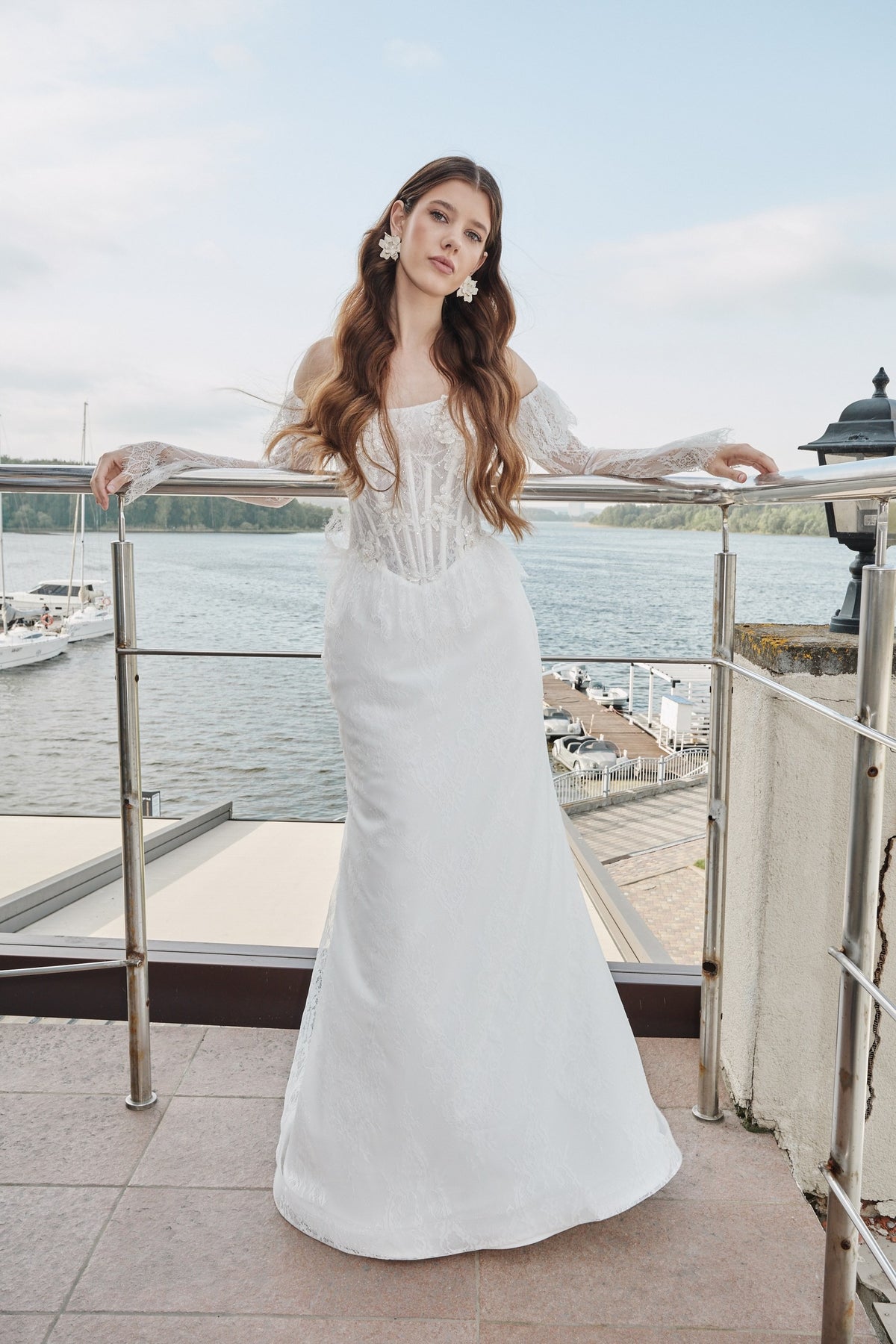 Full-length lace fit-and-flare wedding dress on a waterfront terrace