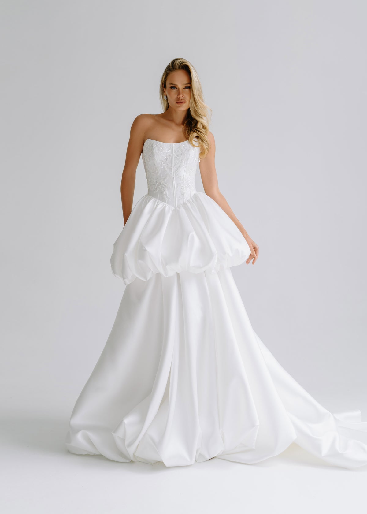 Strapless satin corset dress with a bubble-hem peplum over a long layered skirt with a train