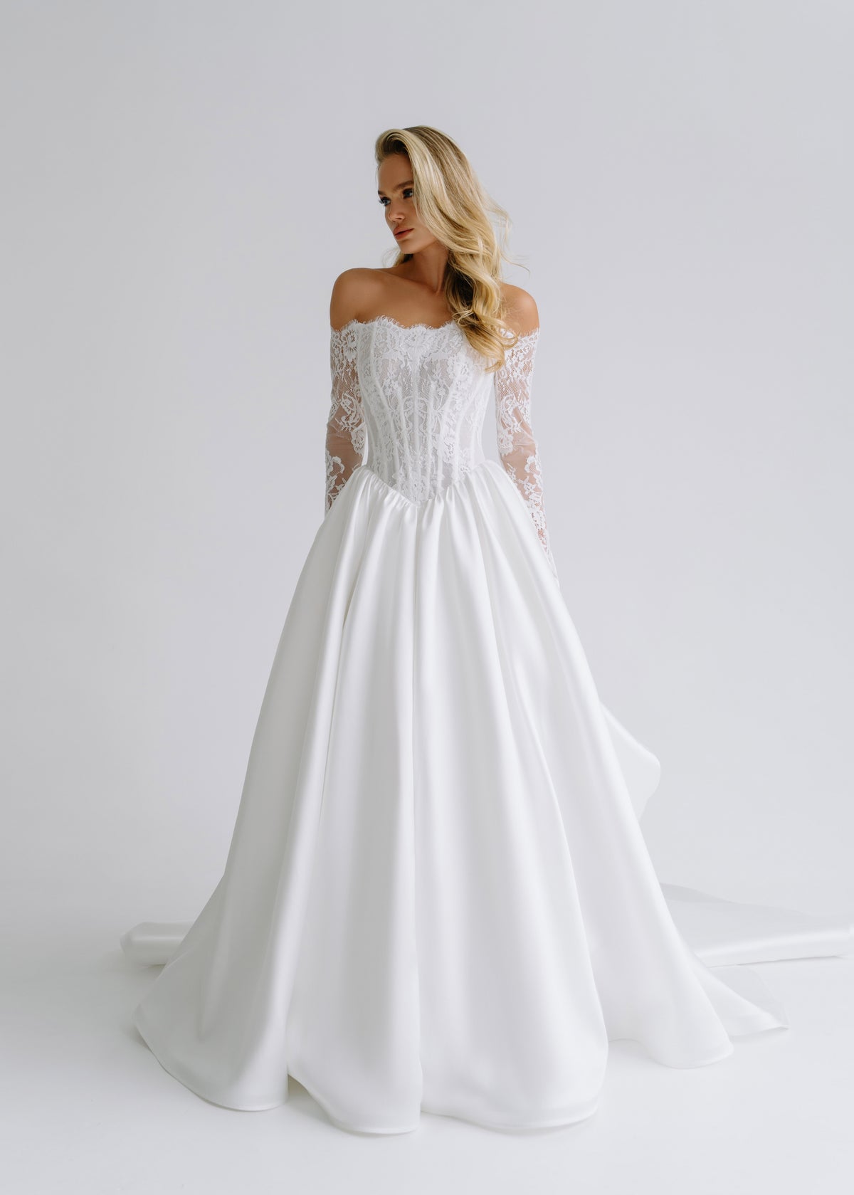 Satin wedding dress with an off-shoulder lace corset, long lace sleeves and a full skirt, front view
