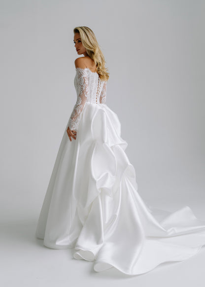 Back view of a satin wedding dress with a draped bow and a long train