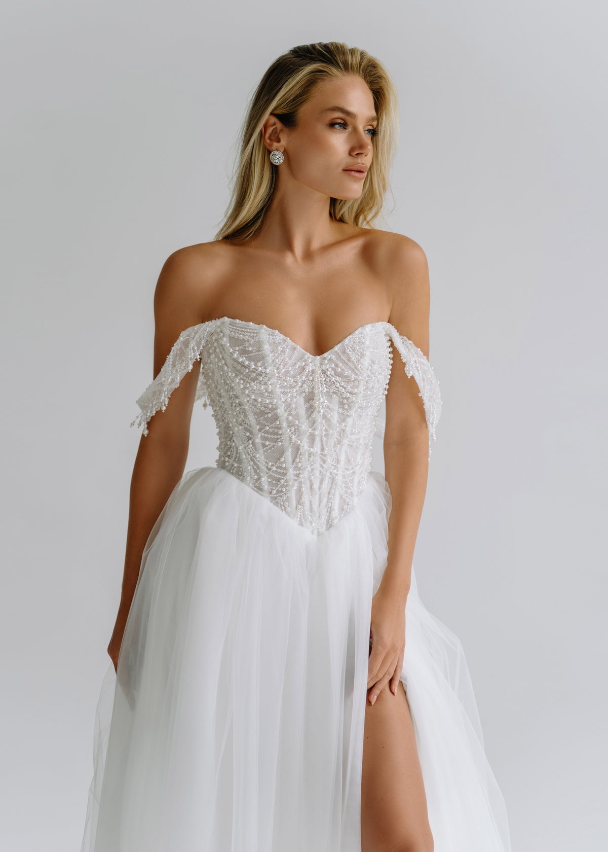 Close-up of a beaded corset with draped off-shoulder straps over a slit tulle skirt