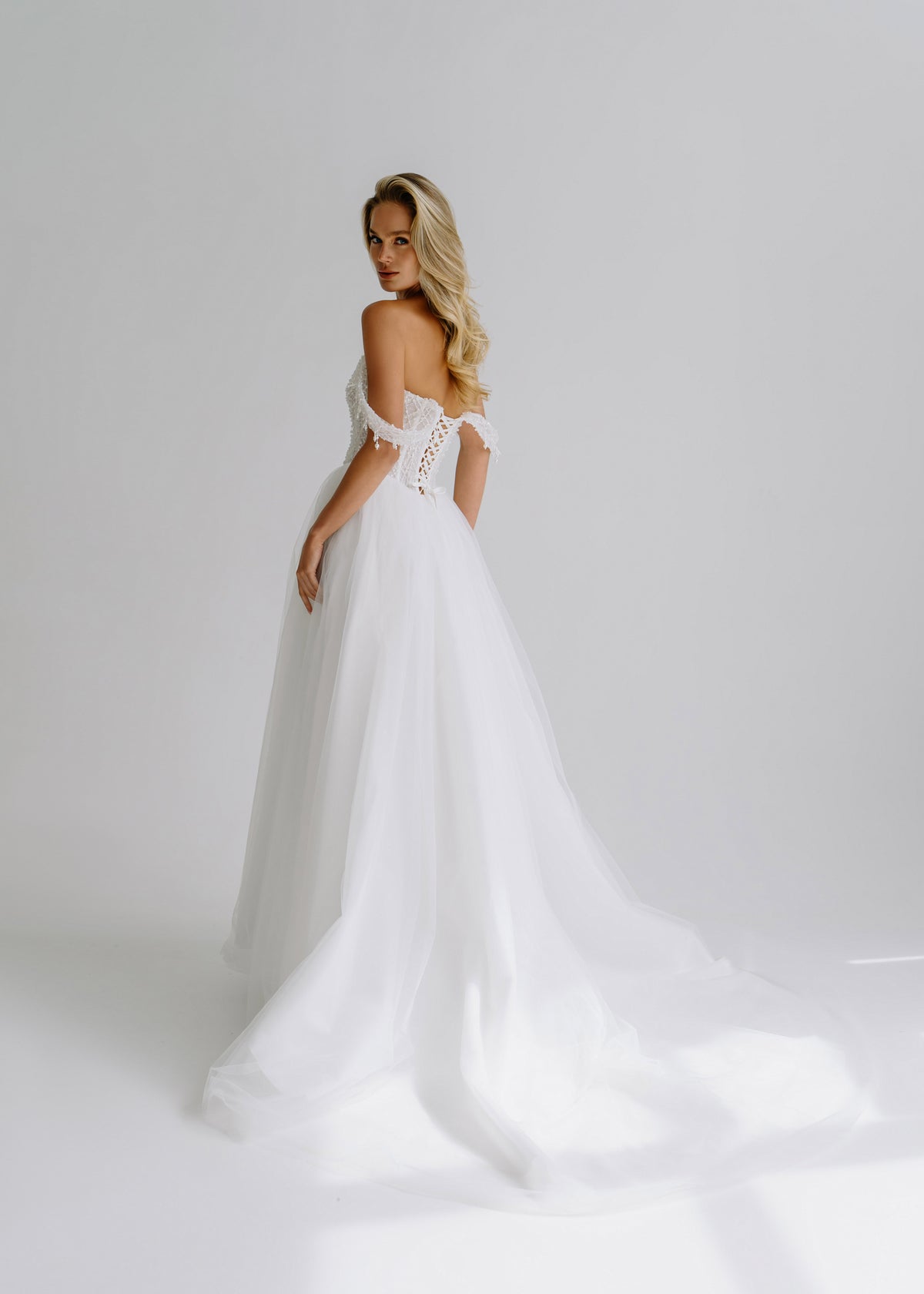 Back view of a tulle wedding dress with a lace-up back and a train