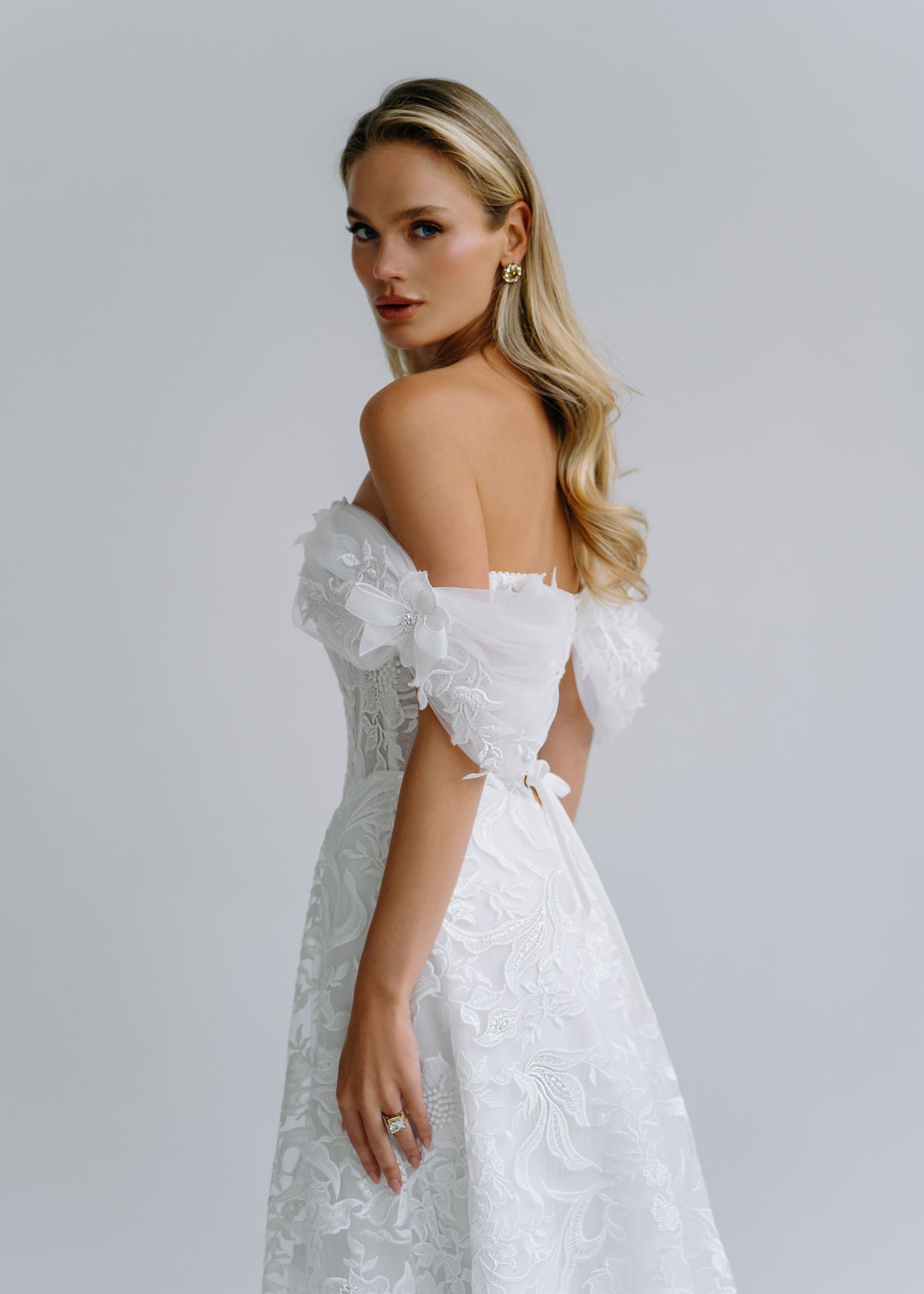 Side view of an off-shoulder neckline with organza flower sleeves and a floral lace skirt