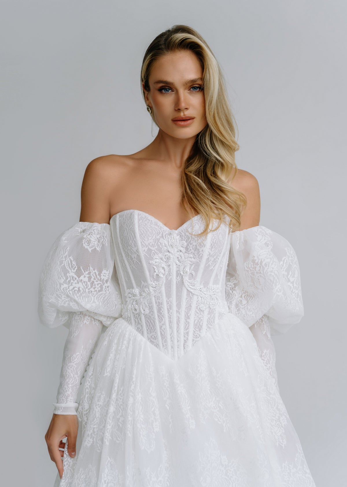 Close-up of an off-shoulder lace corset with puff sleeves and lace cuffs