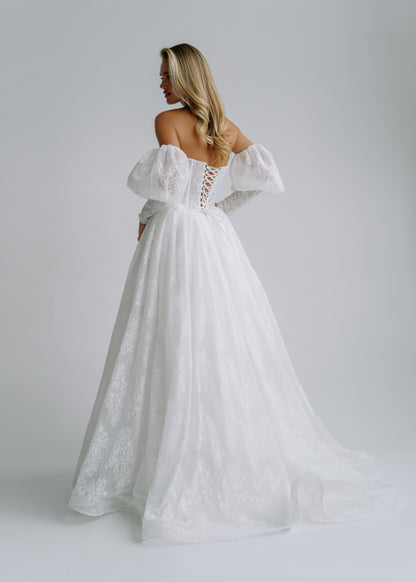 Back view of a lace wedding dress with puff sleeves, a lace-up back and a train