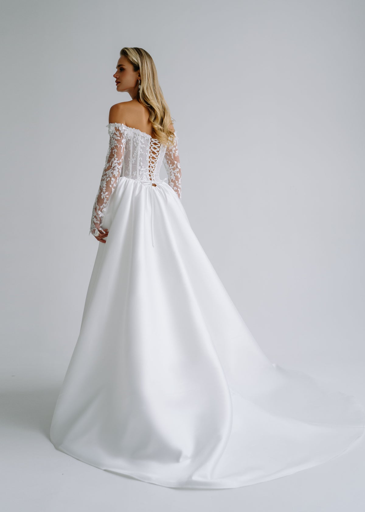 Back view of a satin wedding dress with a lace-up back and a train