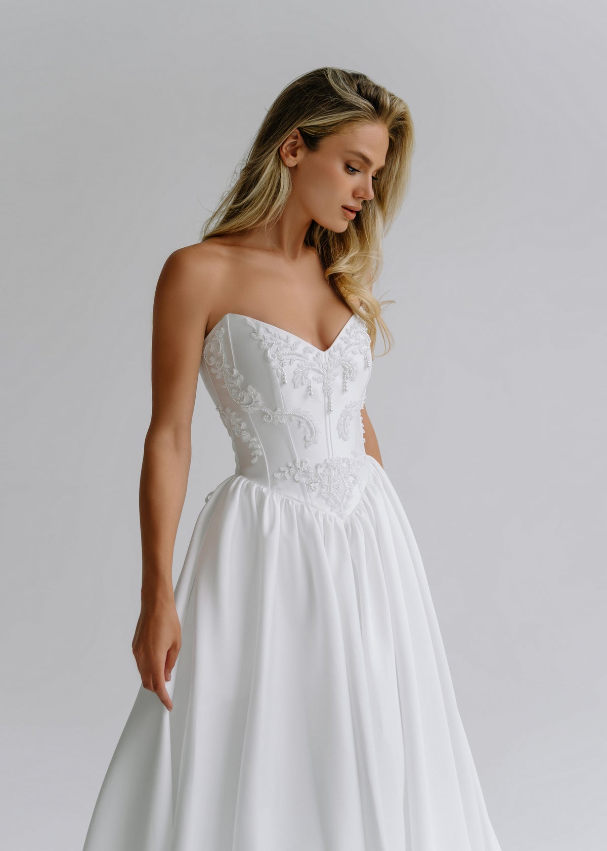 Close-up of an embroidered sweetheart bodice on a satin wedding dress