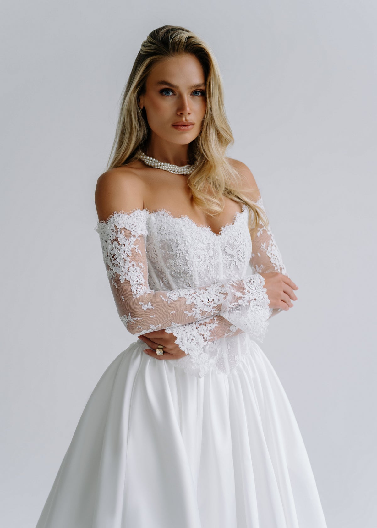Close-up of an off-shoulder lace corset bodice with long lace sleeves, styled with a choker necklace