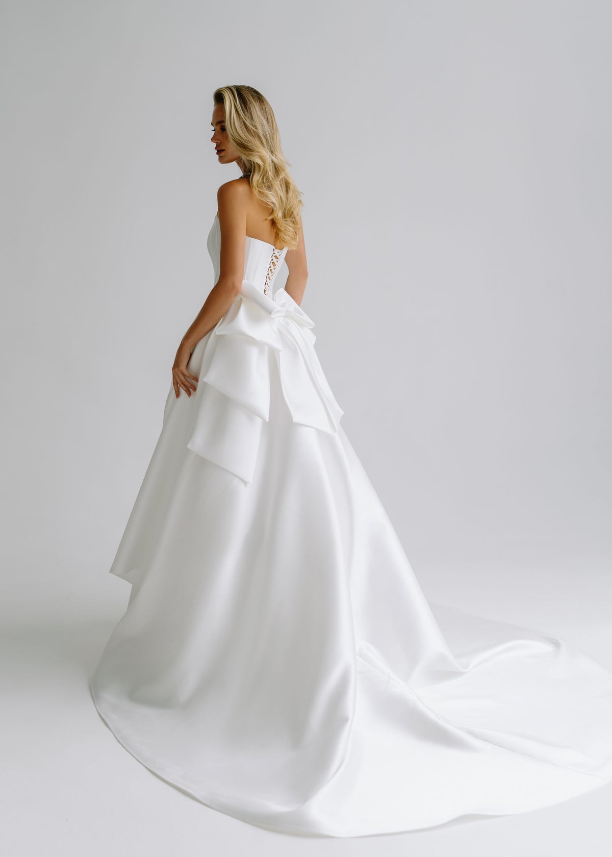 Back view of a satin wedding dress with an oversized layered bow and a train