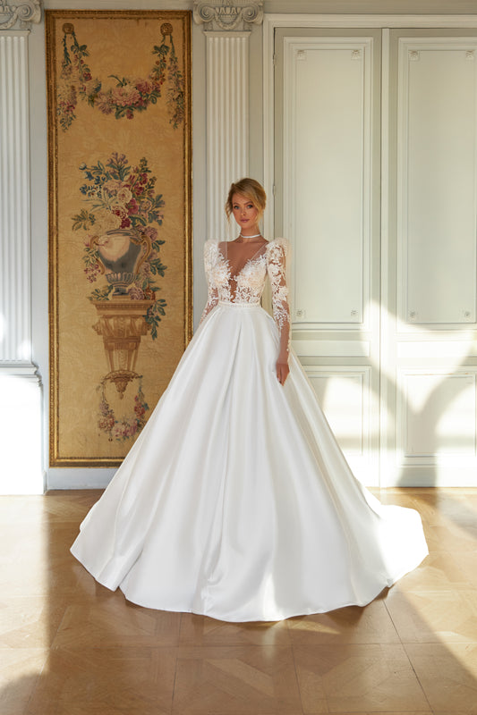  A-line wedding dress with puffy shoulder sleeves, V-shaped bodice, pleated skirt with pockets, embroidered belt, lace appliques, sequin details, and chapel train. Made of lace and taffeta mikado.