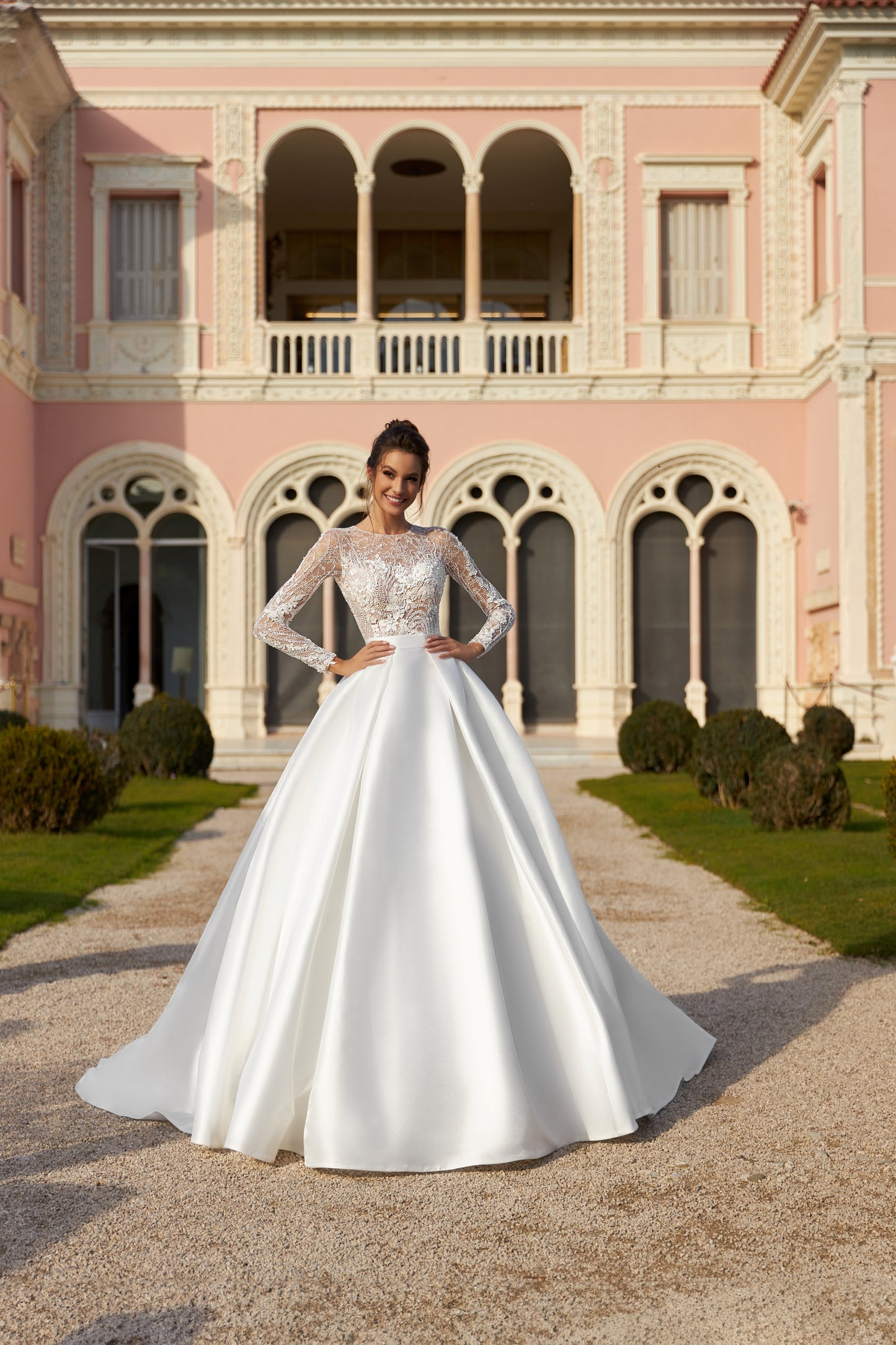 A-line bridal gown with long sleeves, pleated skirt, detachable belt, Chantilly lace, bead and sequin embroidery, and chapel train wedding dress.