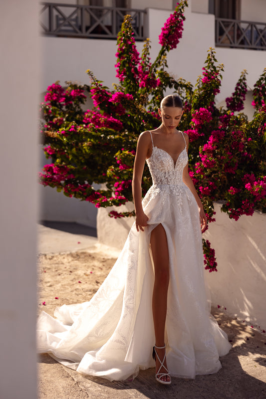 Sleeveless wedding dress with spaghetti straps, V-neckline, and glitter tulle.