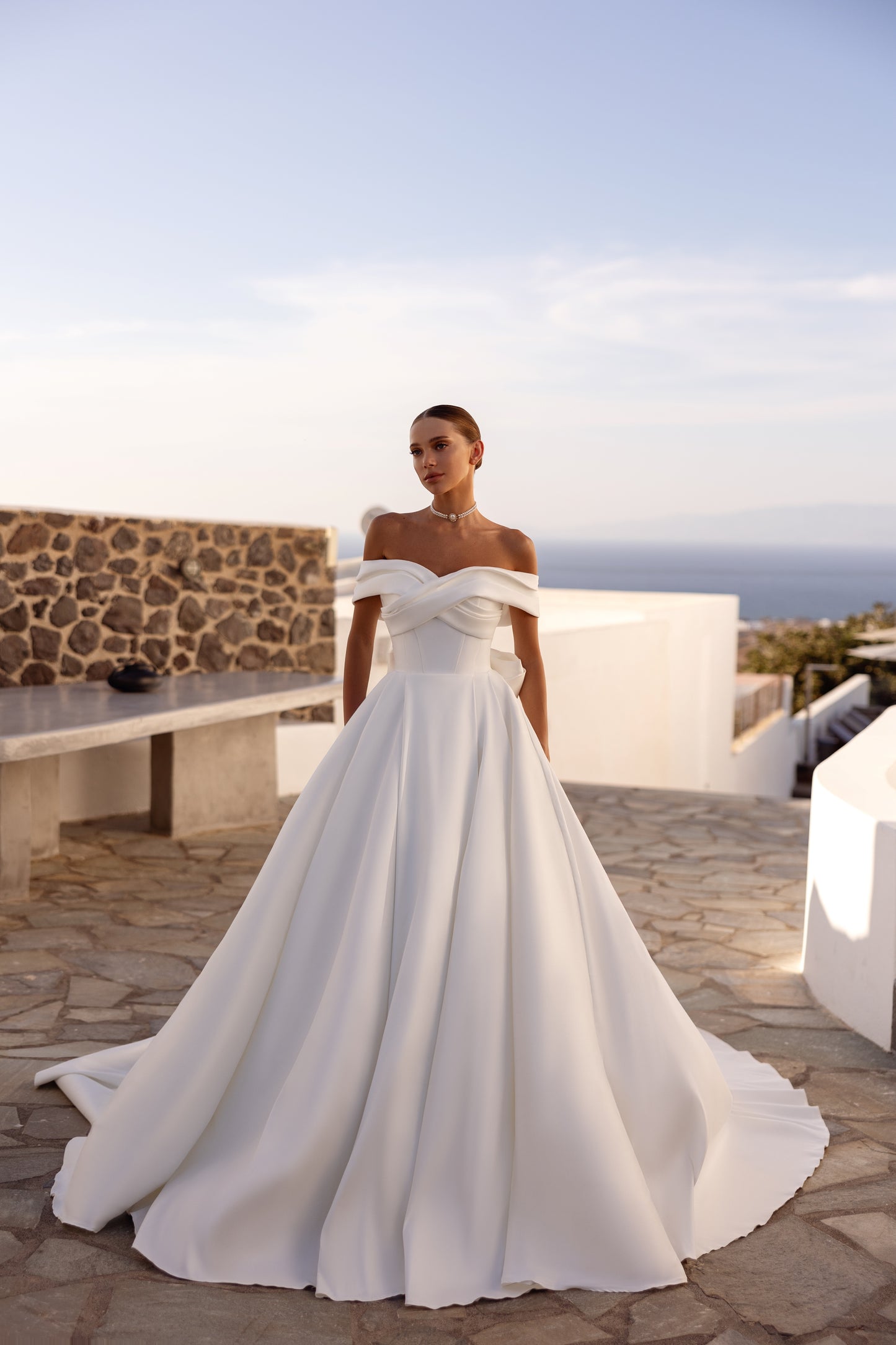 A-line wedding dress with off-the-shoulder neckline and bow.