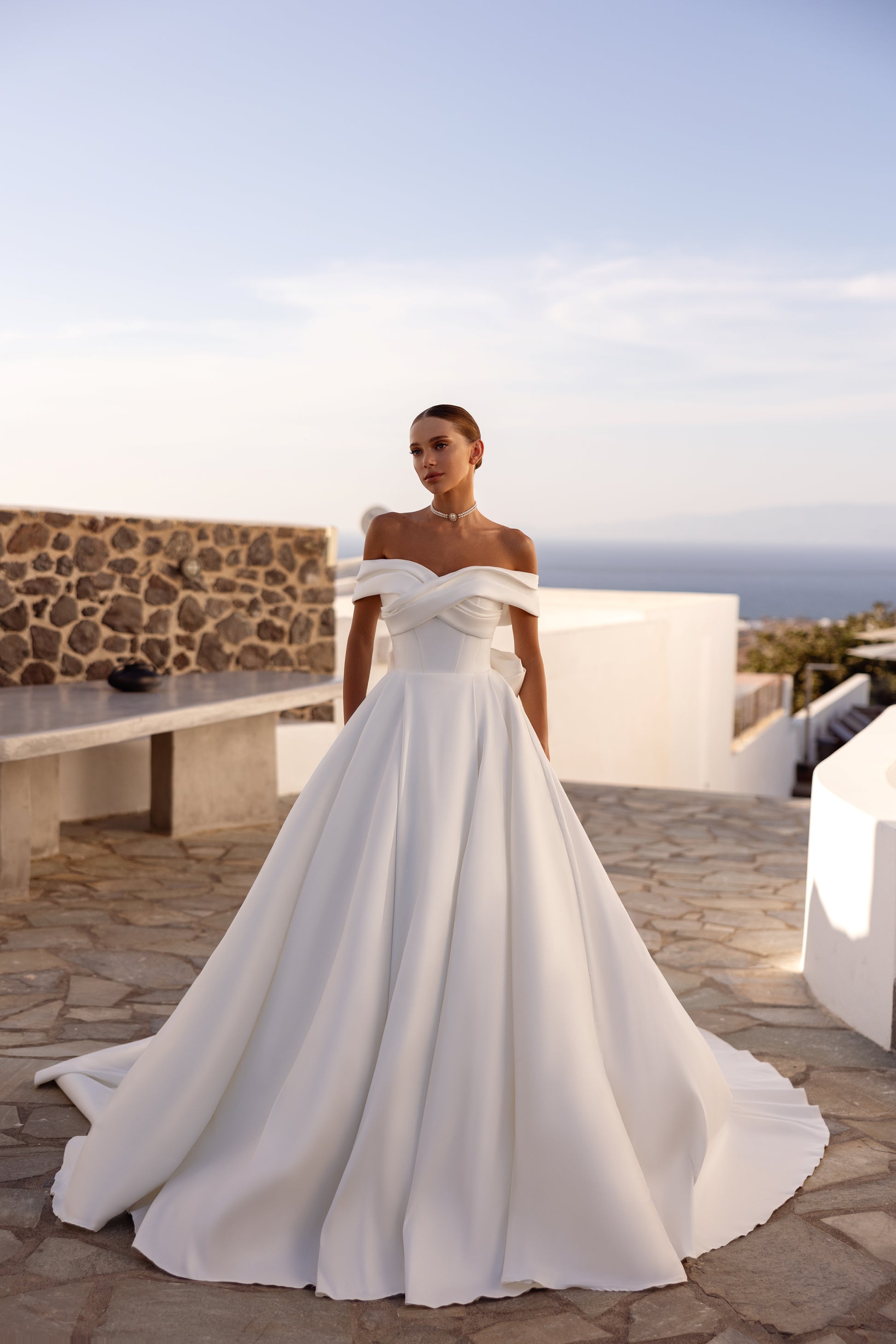 A-line wedding dress with off-the-shoulder neckline and bow.