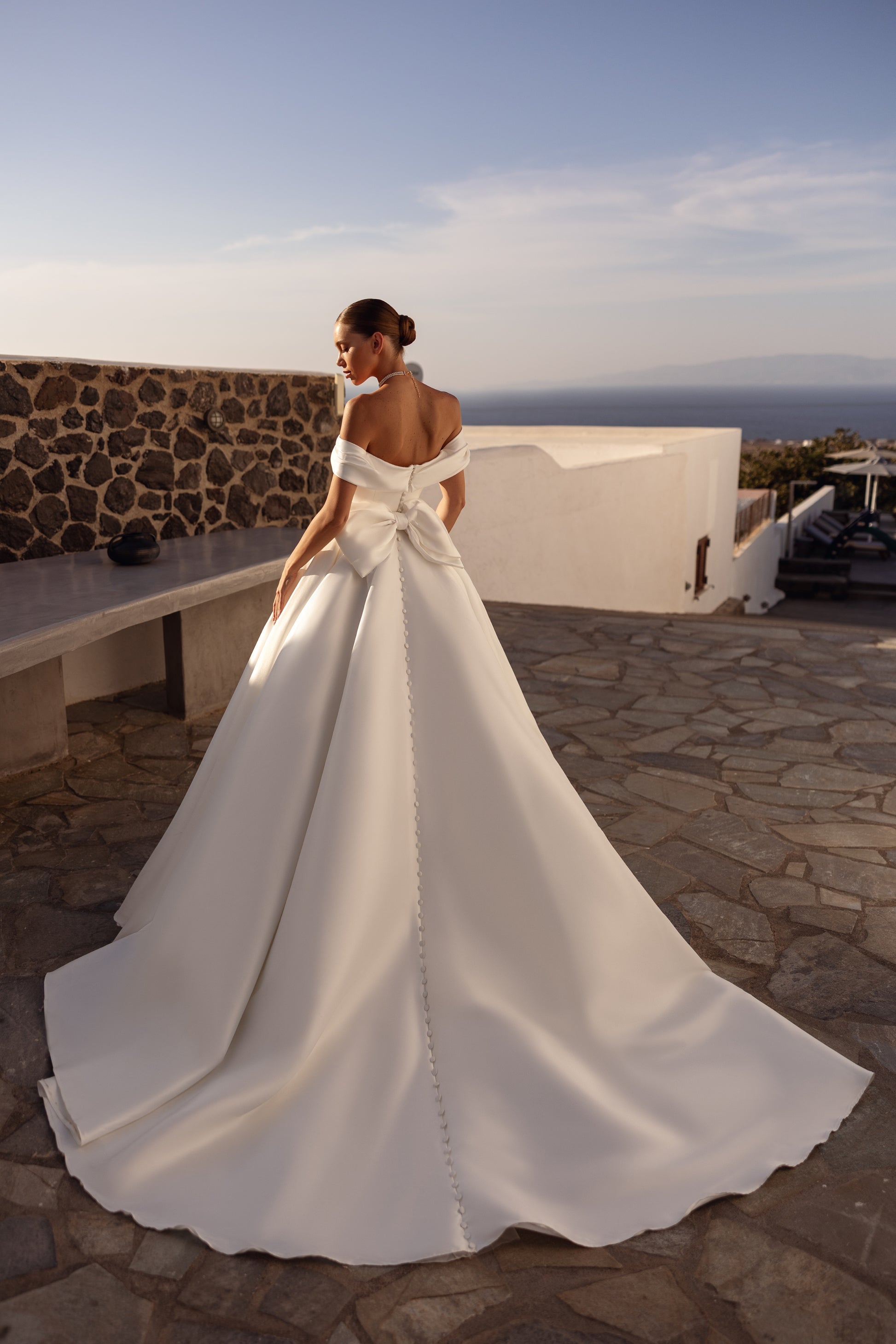 A-line wedding dress with off-the-shoulder neckline and bow.