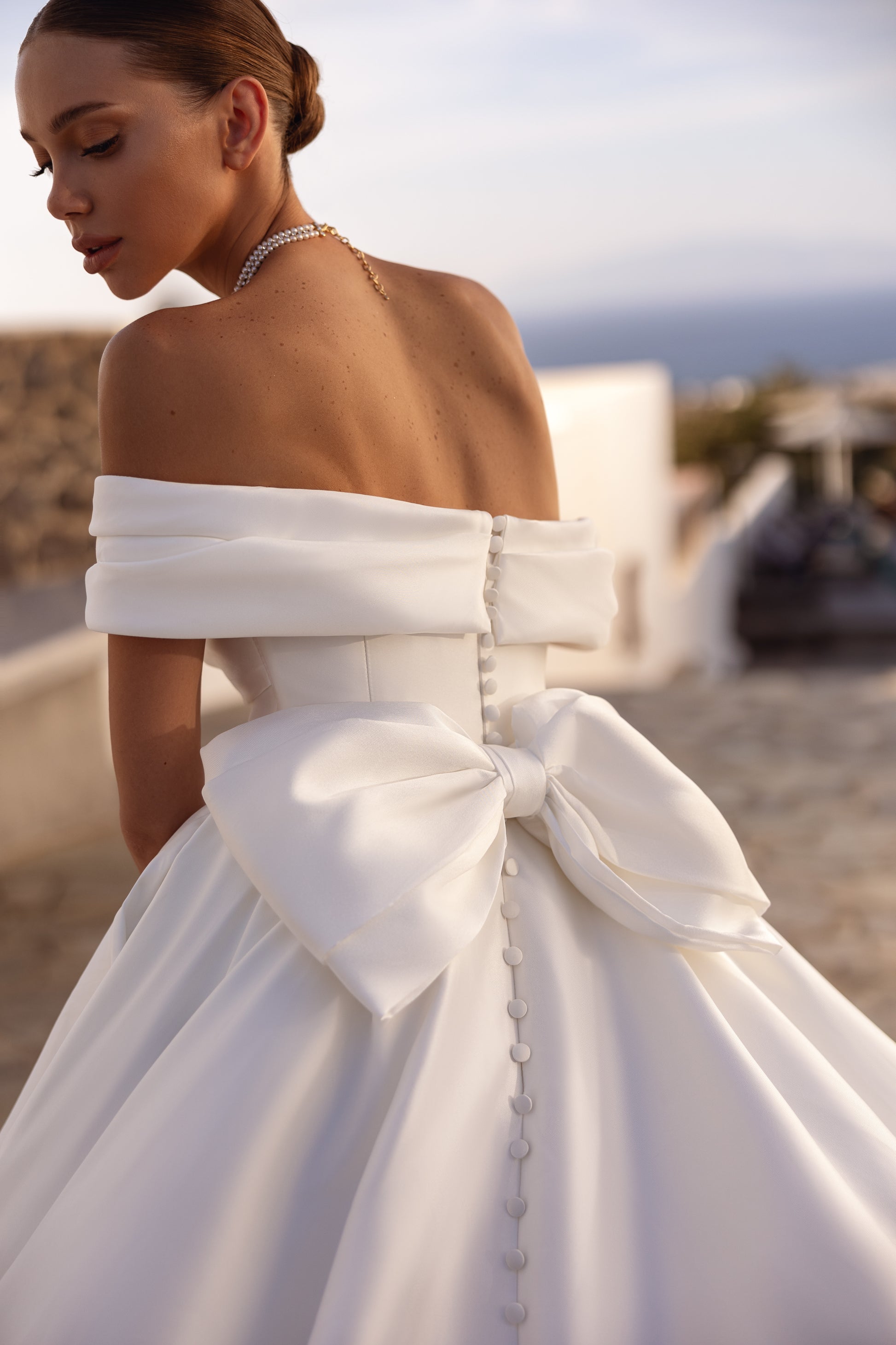 A-line wedding dress with off-the-shoulder neckline and bow.