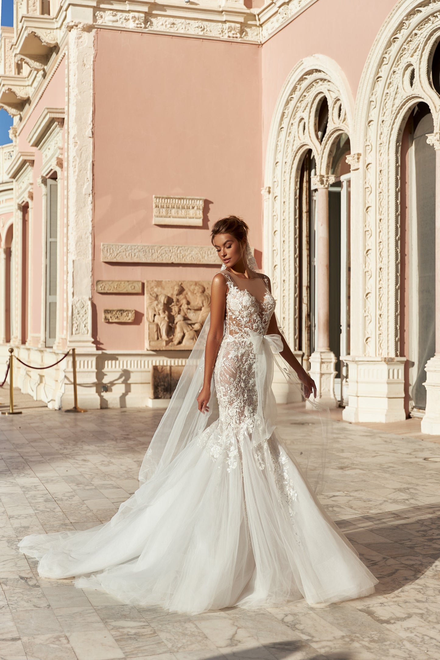 Modern mermaid wedding dress with knee-high cut, detachable waist bow, lace appliques, bead and pearl embroidery, 50 cm train, and matching veil. Made of lace and tulle for a timeless bridal look.