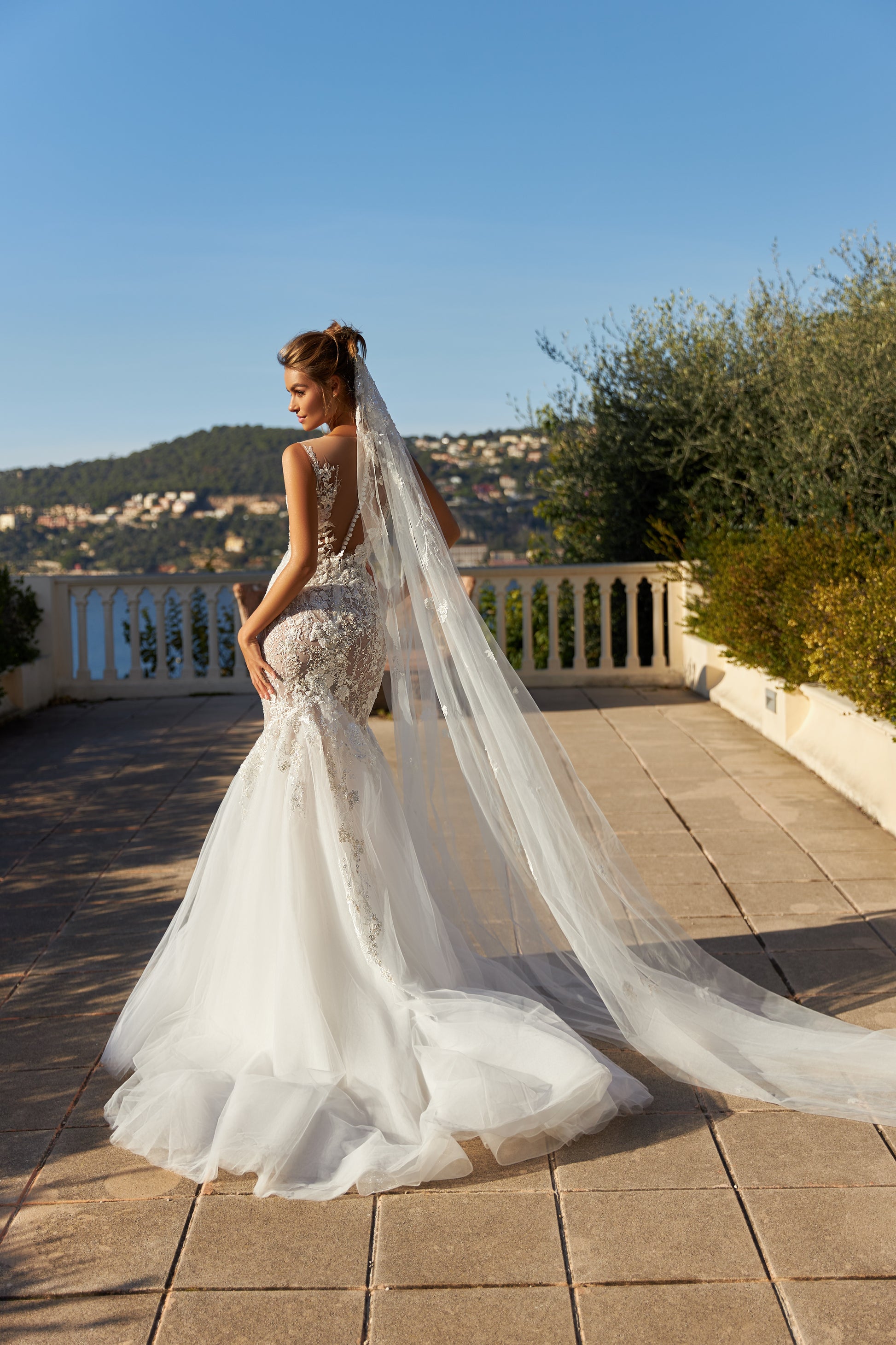 Modern mermaid wedding dress with knee-high cut, detachable waist bow, lace appliques, bead and pearl embroidery, 50 cm train, and matching veil. Made of lace and tulle for a timeless bridal look.