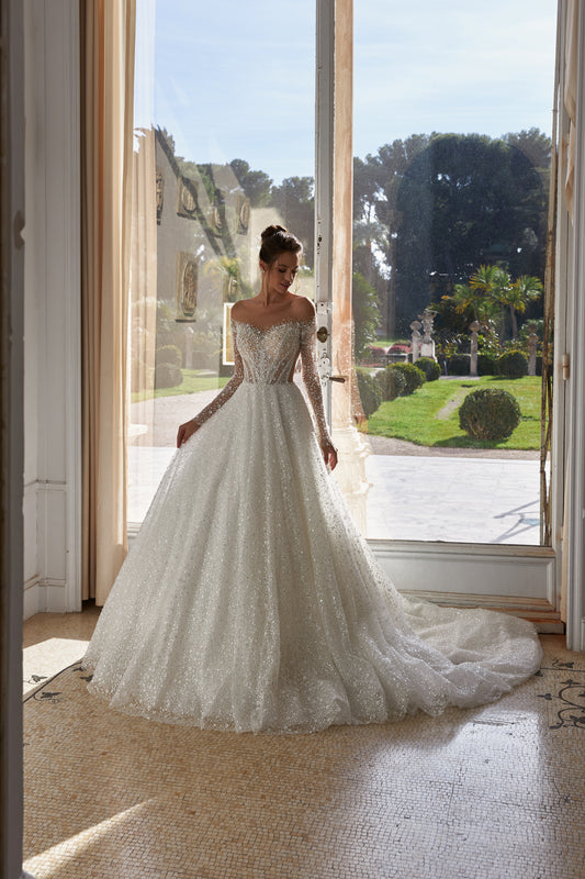 A-line bridal gown with illusion long sleeves, closed back, pearl and crystal embroidery, exclusive lace fabric, and chapel train.