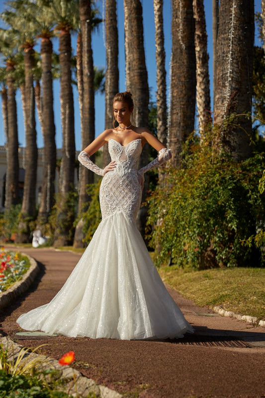 Mermaid silhouette wedding dress with V-neckline, open back, removable gloves, lace appliques, bead and sequin embroidery, and a fishtail train. Made from lace and tulle.