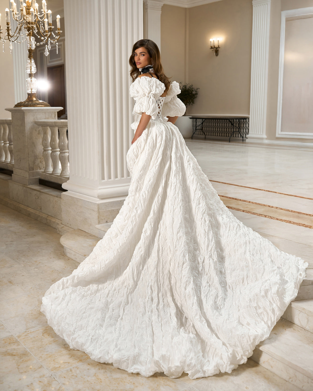 Rear three-quarter view of the taffeta and lace wedding dress with puff sleeves and a full sweeping train.