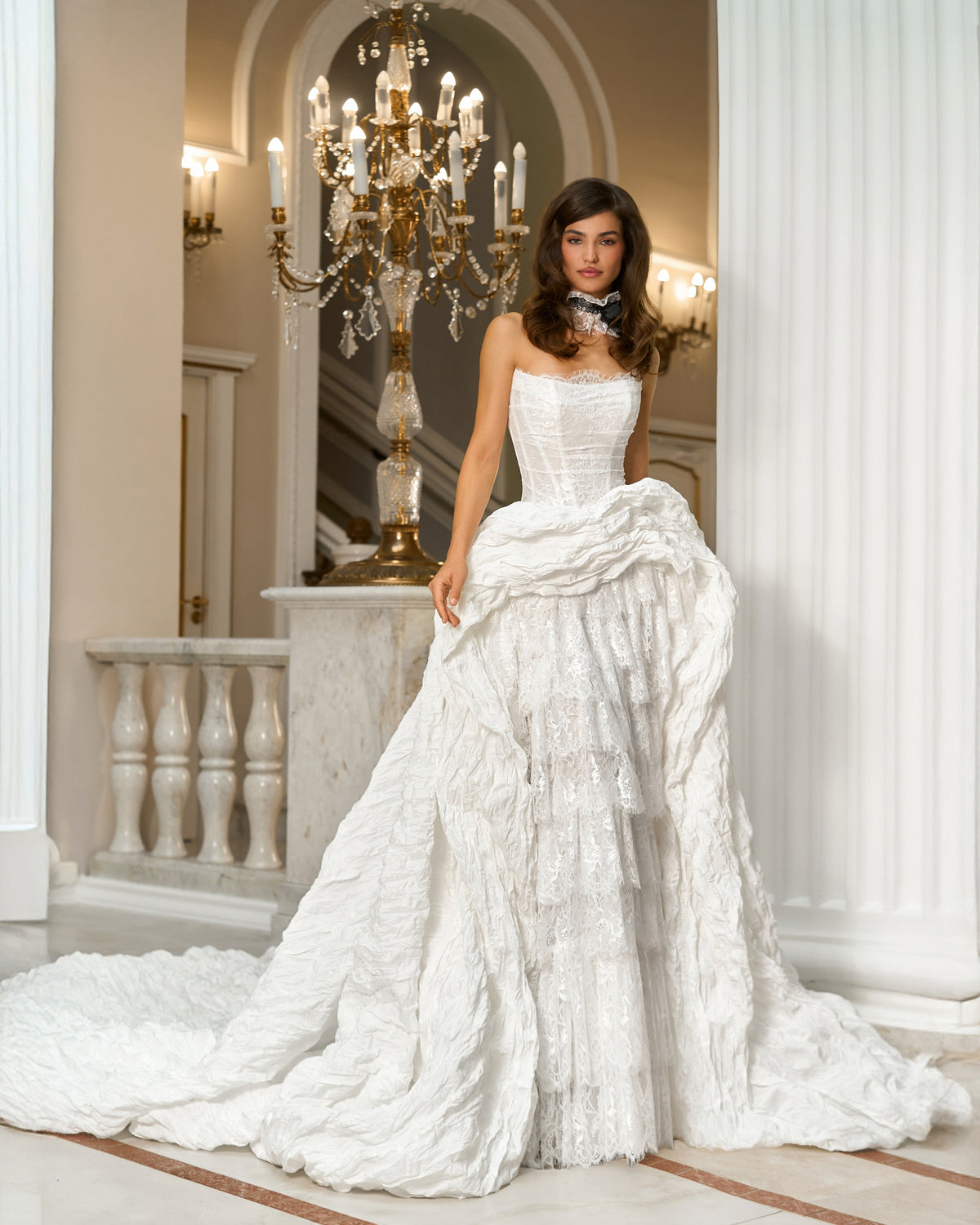 Front view of the strapless wedding dress without sleeves, showing the draped high-low skirt and long train.