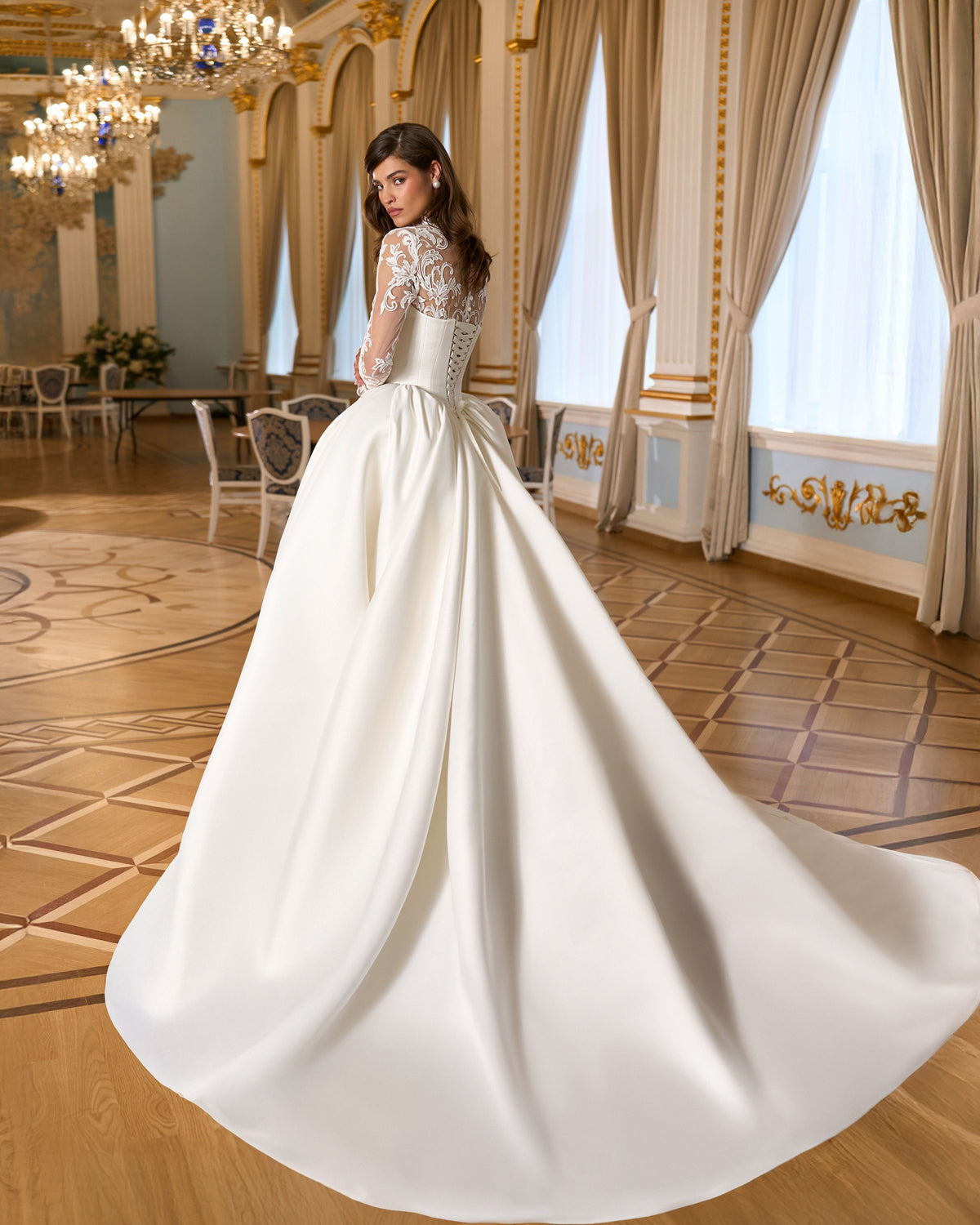 Rear three-quarter view of the basque waist wedding dress showing the floral lace back, full skirt and sweeping train.