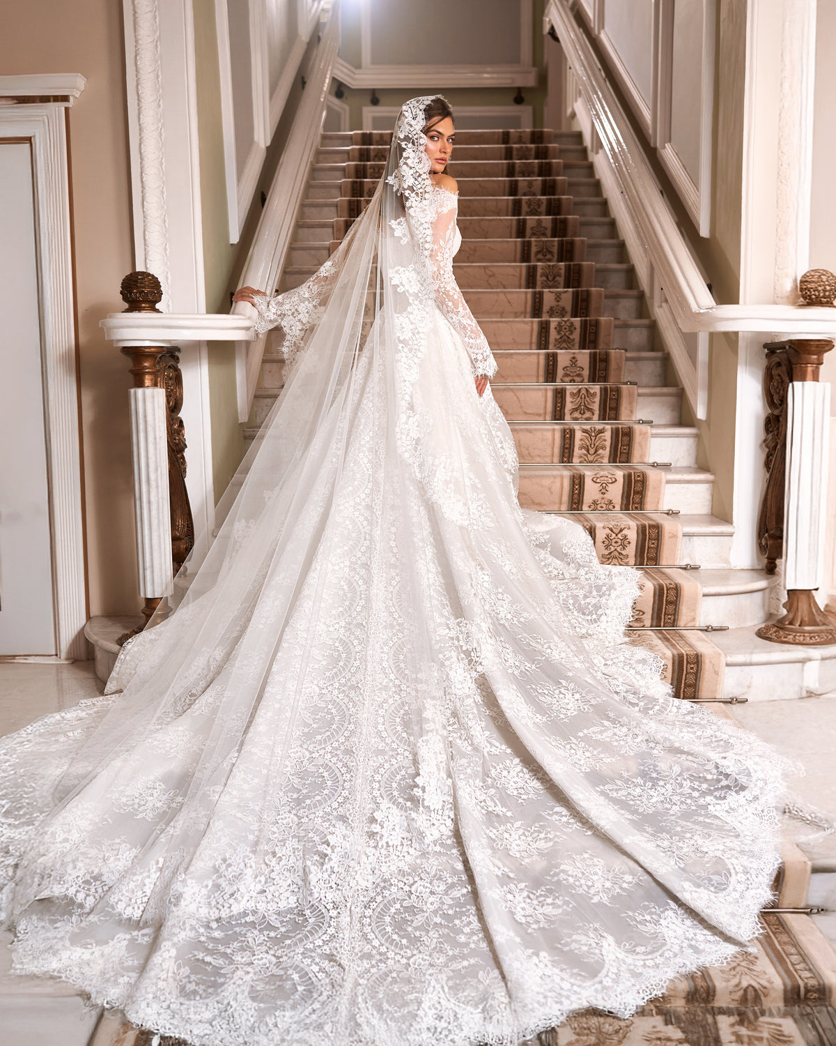 A-line lace wedding dress seen from behind with a wide scalloped lace train and a long sheer veil with floral appliques.