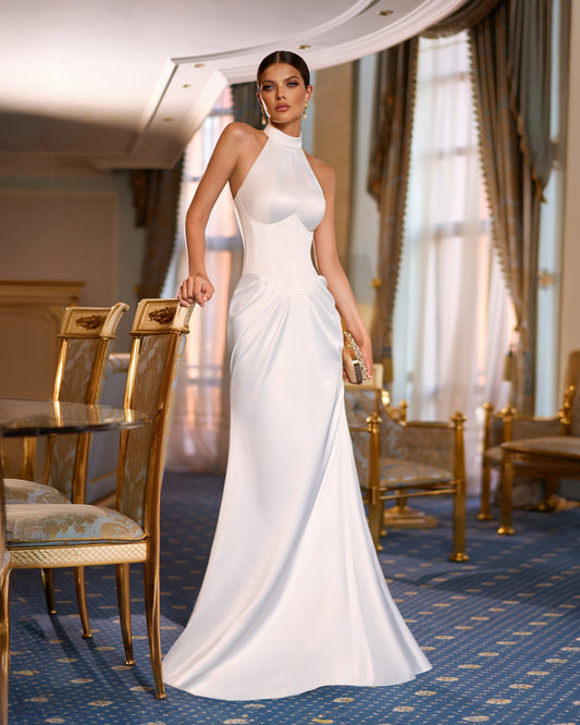 Bride wearing satin fitted sleeveless halter neck wedding dress with drop-down waist, draped hip detail, and sweep train.