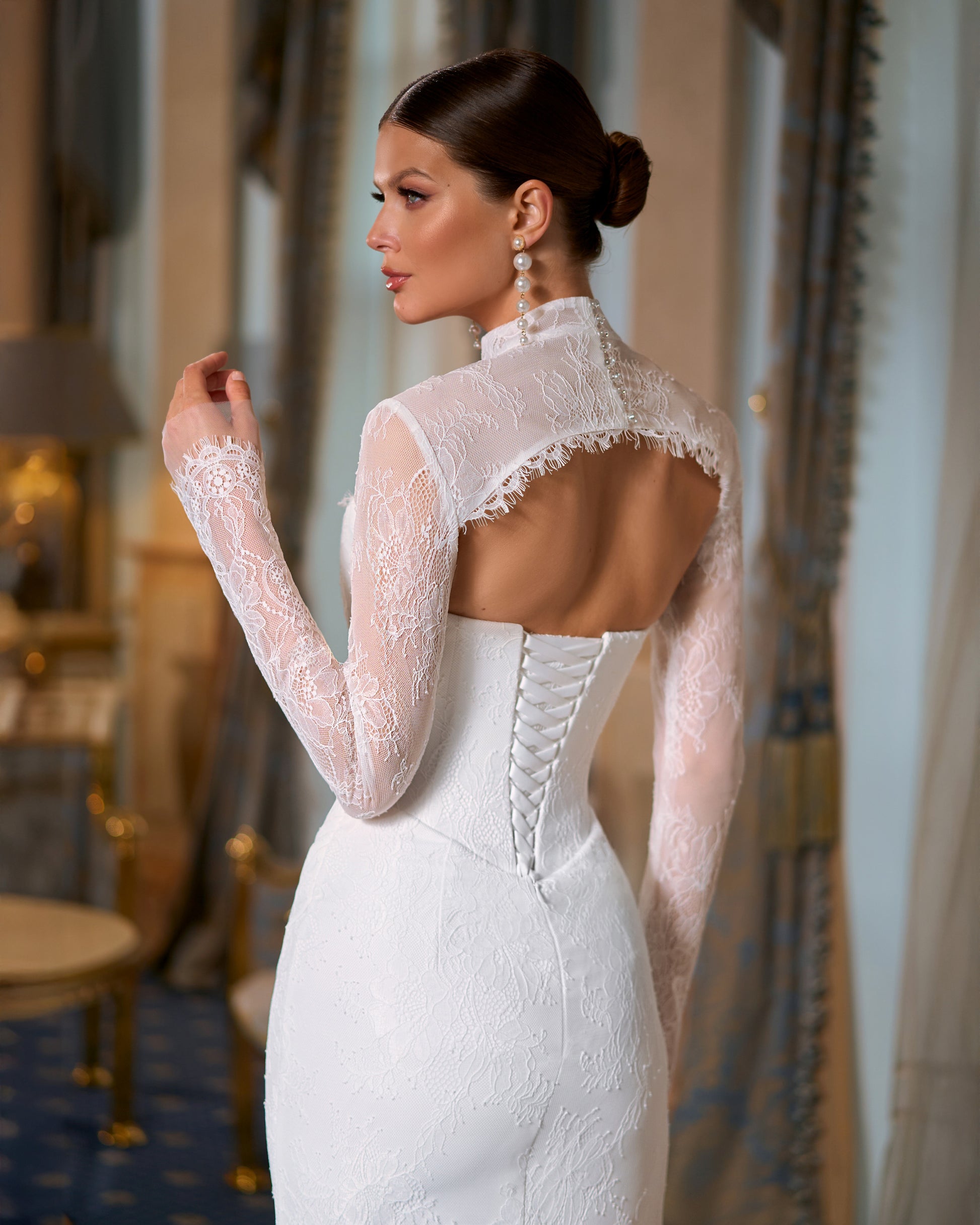 Bride in fitted lace wedding dress with sweetheart neckline, removable long-sleeve lace bolero, thigh-high slit, and chapel train.