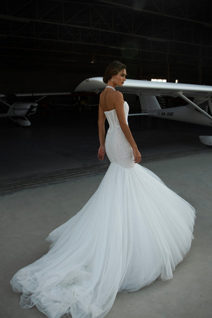 Strapless mermaid wedding dress with corrugated tulle, pearl detailing, fit and flare silhouette, and sweeping fishtail train for striking modern bridal look