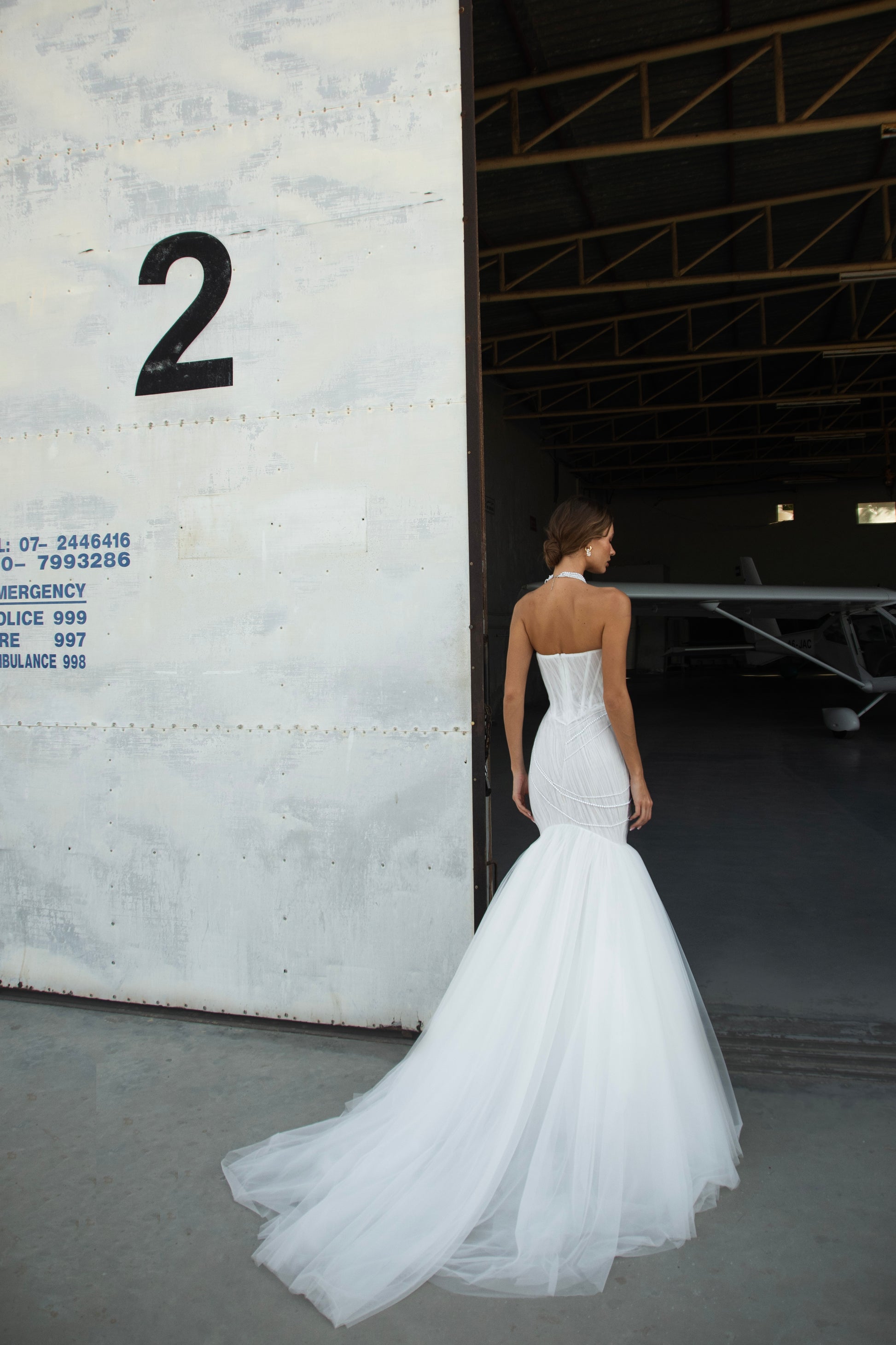 Strapless mermaid wedding dress with corrugated tulle, pearl detailing, fit and flare silhouette, and sweeping fishtail train for striking modern bridal look