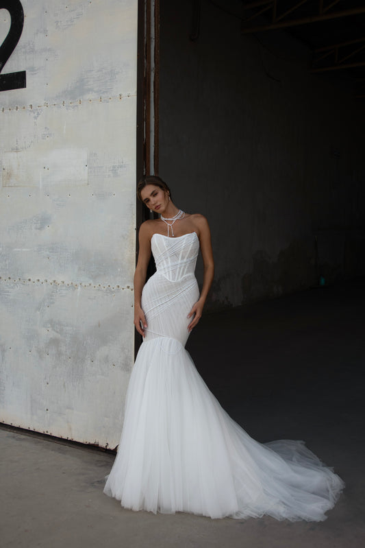 Strapless mermaid wedding dress with corrugated tulle, pearl detailing, fit and flare silhouette, and sweeping fishtail train for striking modern bridal look