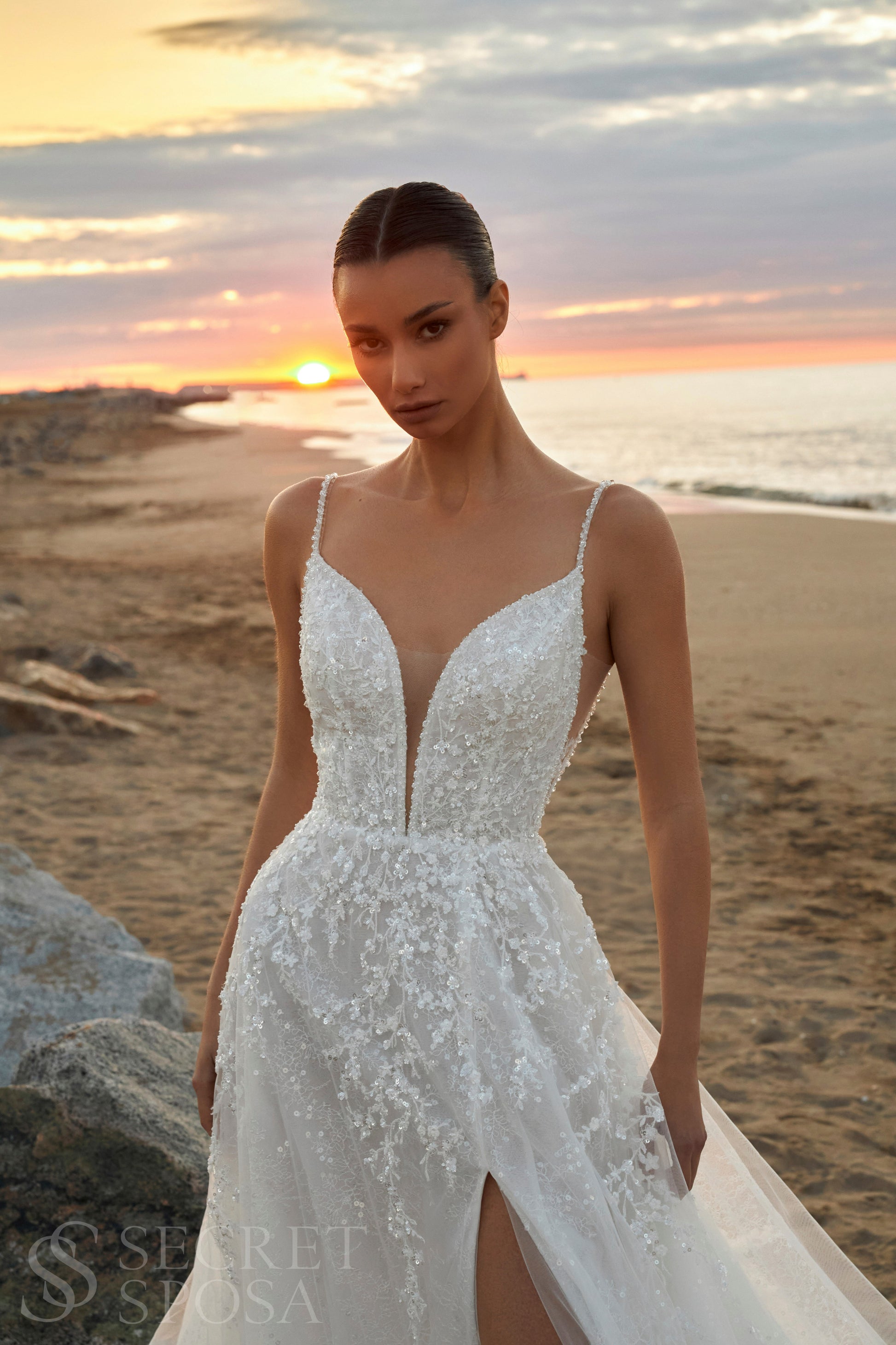 Bride in A-line halter wedding dress with spaghetti straps, sequin embroidered lace tulle skirt, high slit, and open back.