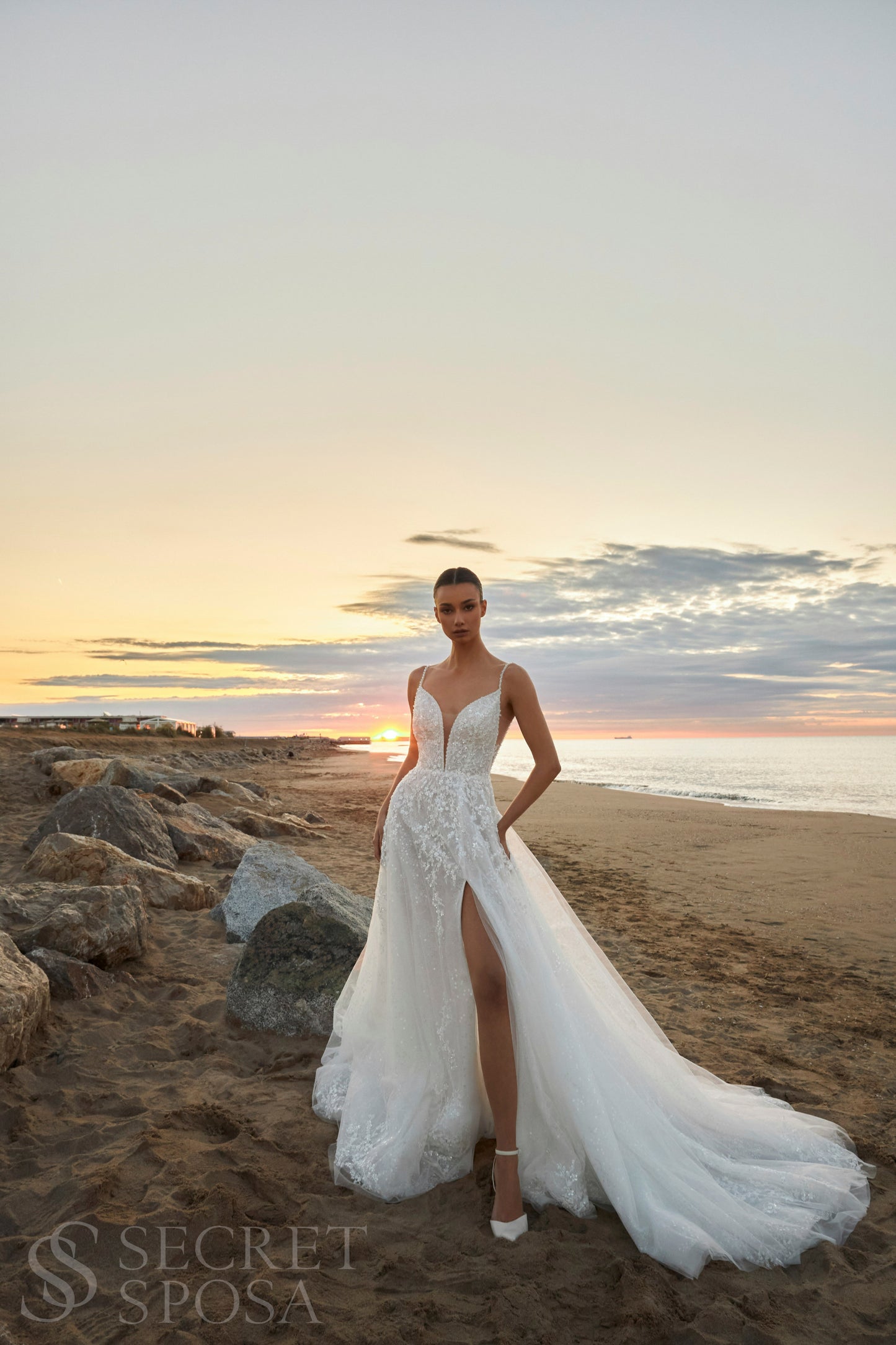 Bride in A-line halter wedding dress with spaghetti straps, sequin embroidered lace tulle skirt, high slit, and open back.