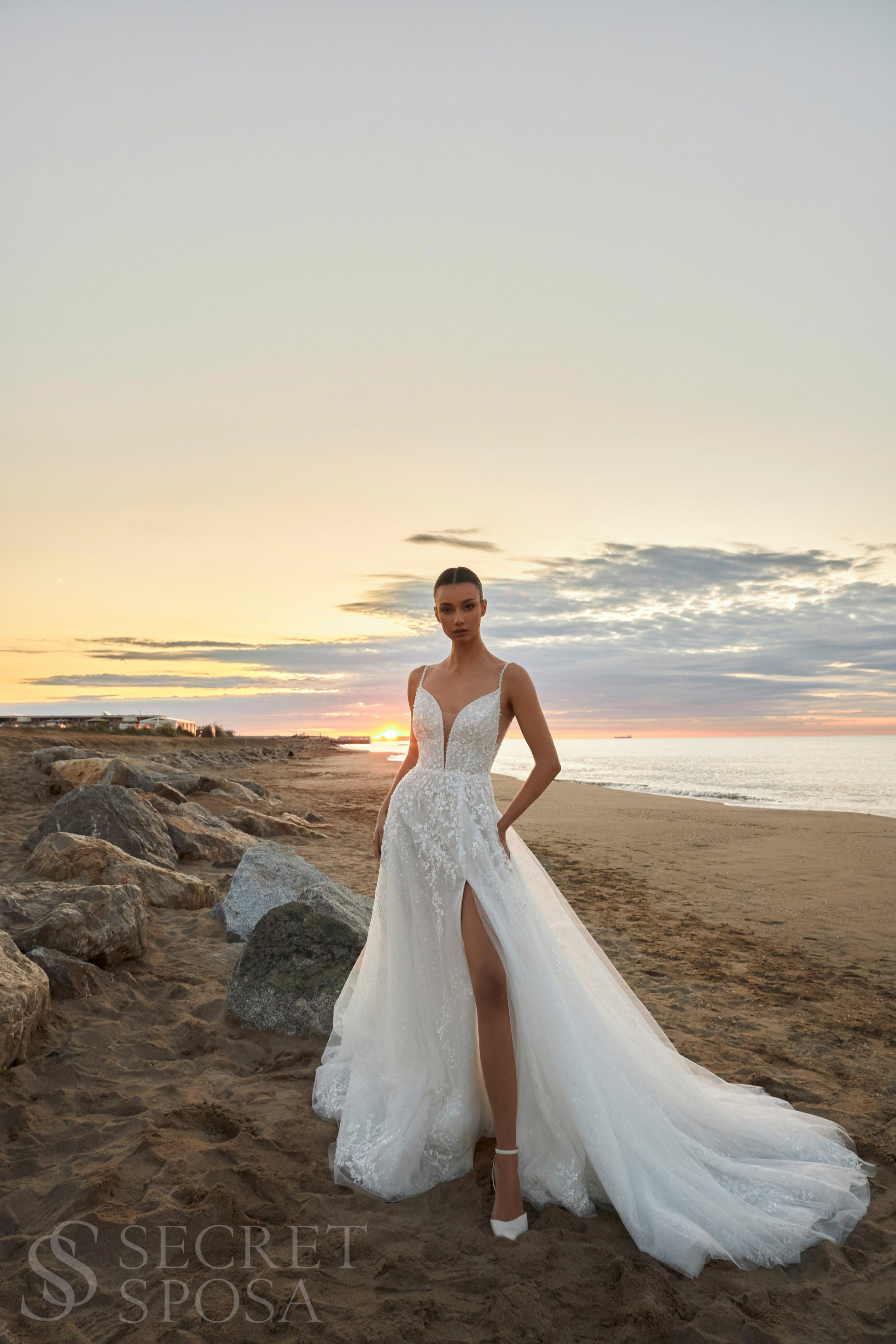 Bride in A-line halter wedding dress with spaghetti straps, sequin embroidered lace tulle skirt, high slit, and open back.