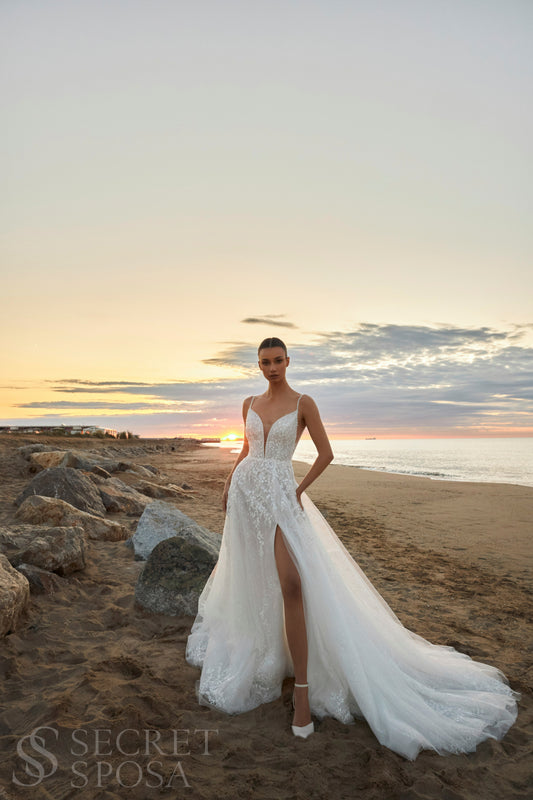 Bride in A-line halter wedding dress with spaghetti straps, sequin embroidered lace tulle skirt, high slit, and open back.