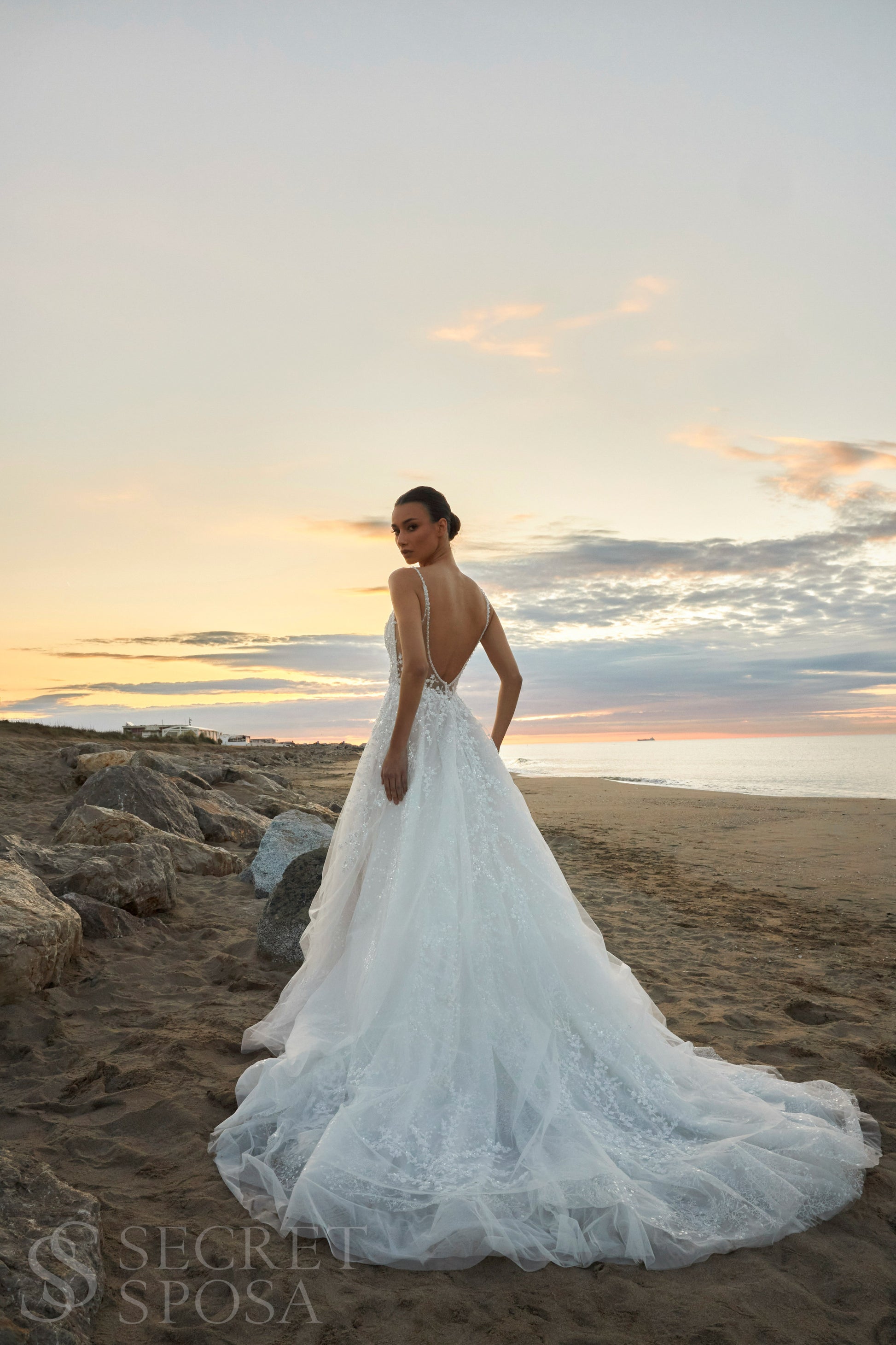 Bride in A-line halter wedding dress with spaghetti straps, sequin embroidered lace tulle skirt, high slit, and open back.