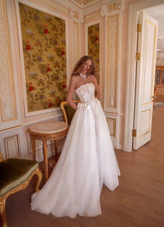 Strapless lace corset wedding gown with satin bows and voluminous tulle skirt.