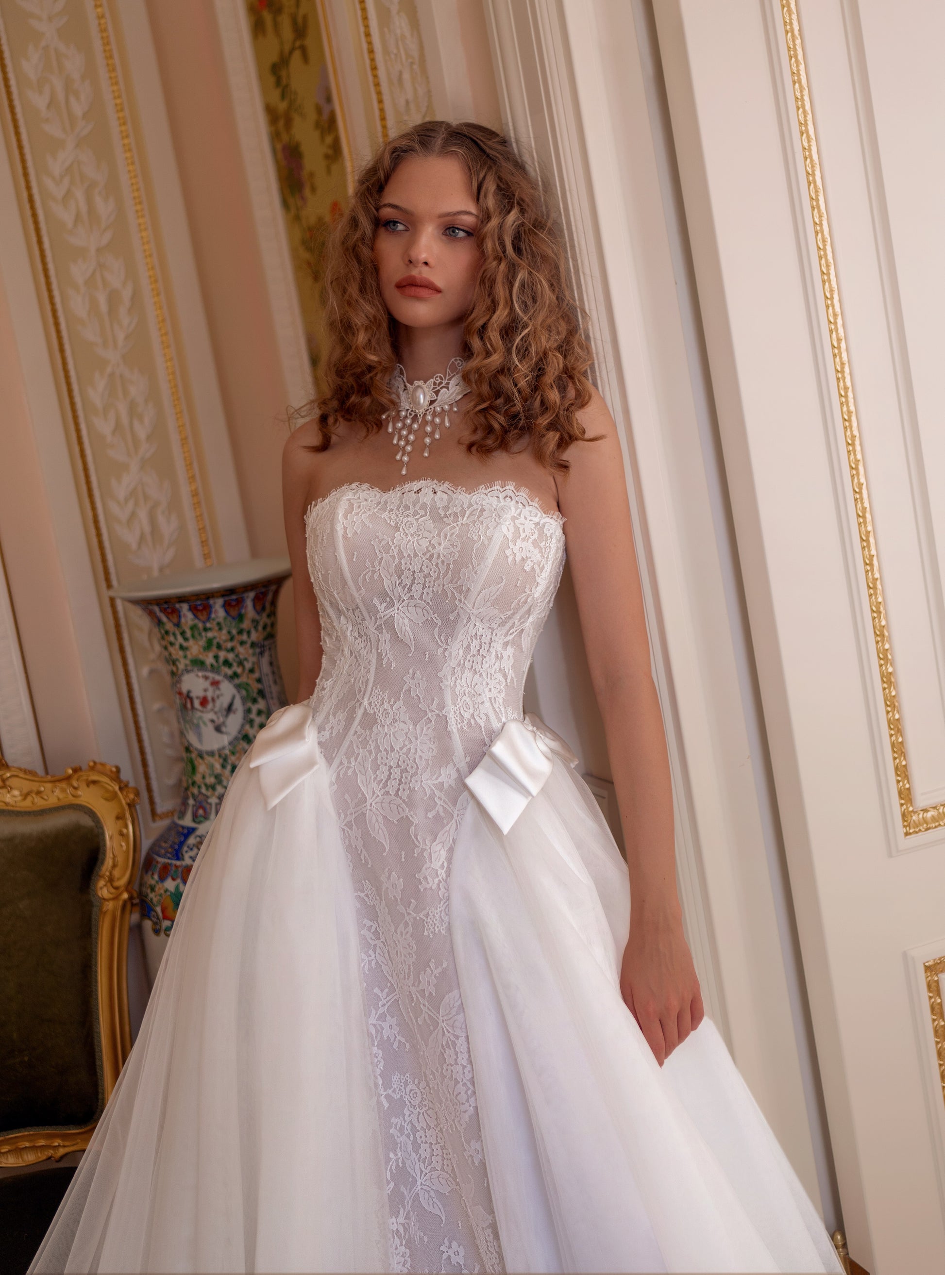 Strapless lace corset wedding gown with satin bows and voluminous tulle skirt.