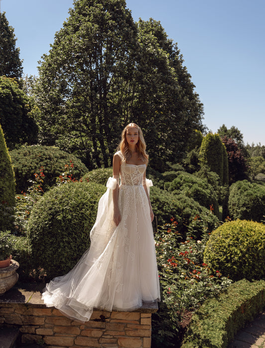 Sleeveless wedding dress with tulle gloves and lace details.