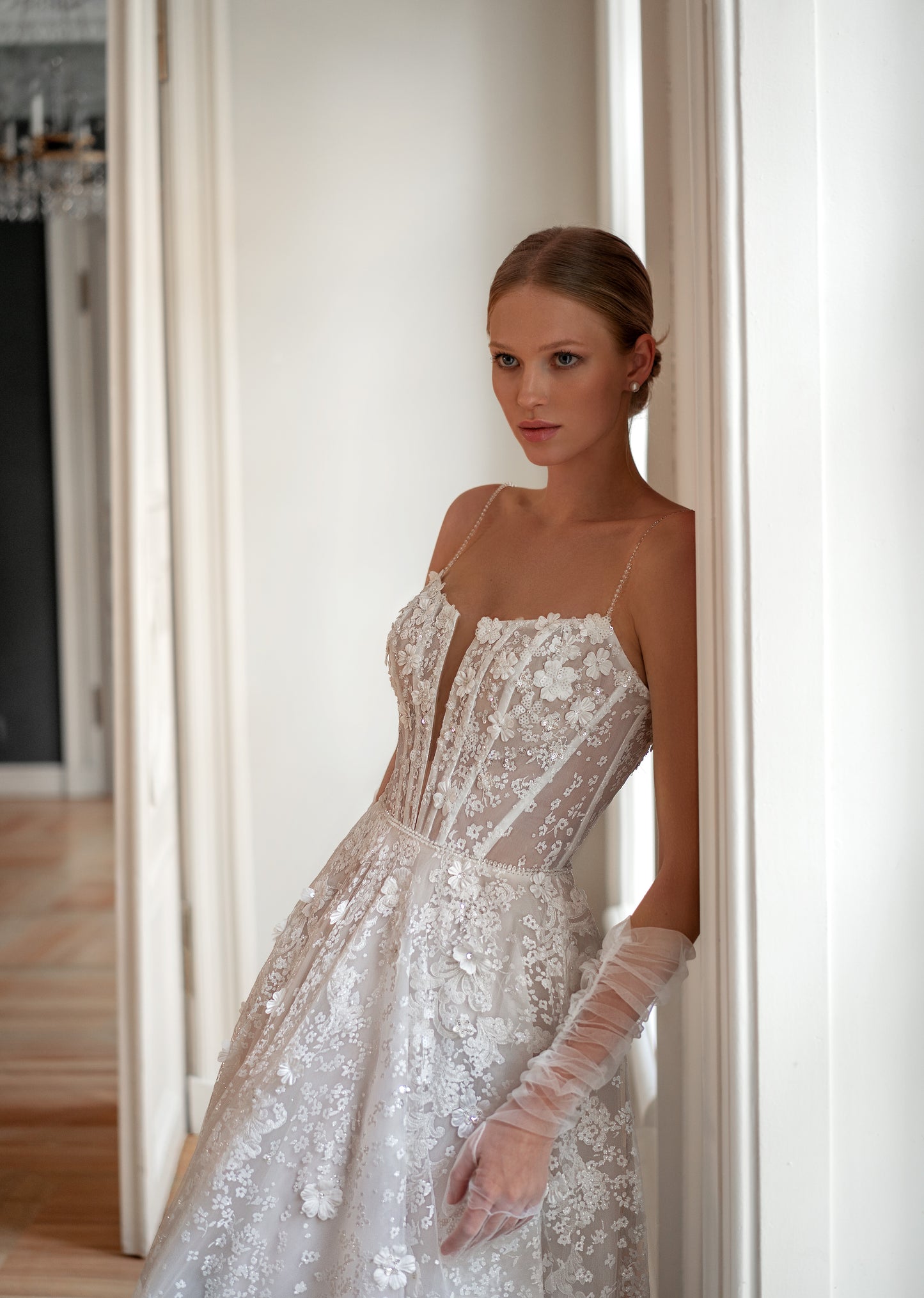 A-line bridal gown featuring a plunging neckline, removable tulle gloves, and a court train.