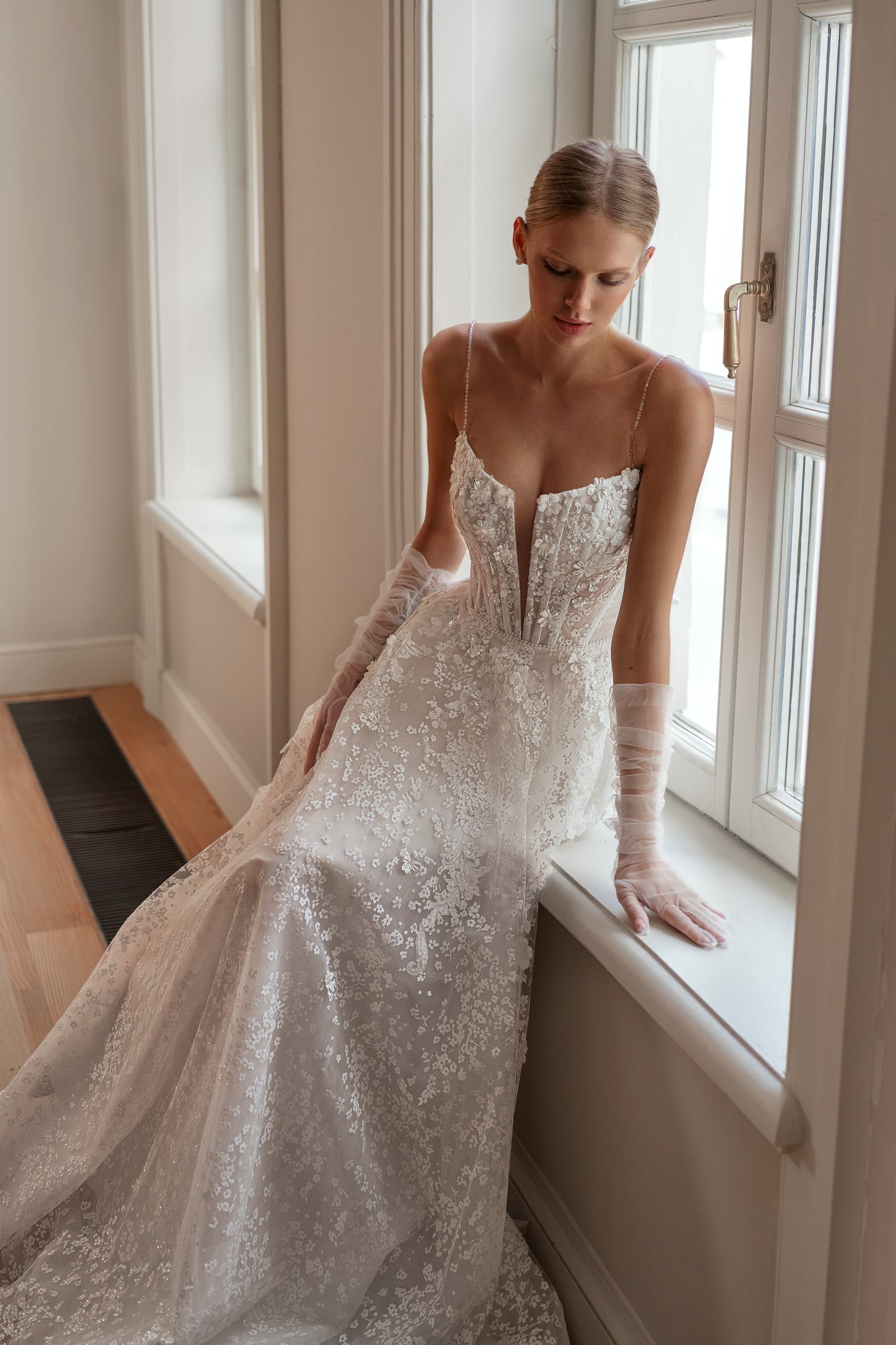 Sleeveless bridal gown with a deep V-neckline, sparkling glitter lace, and removable tulle gloves.