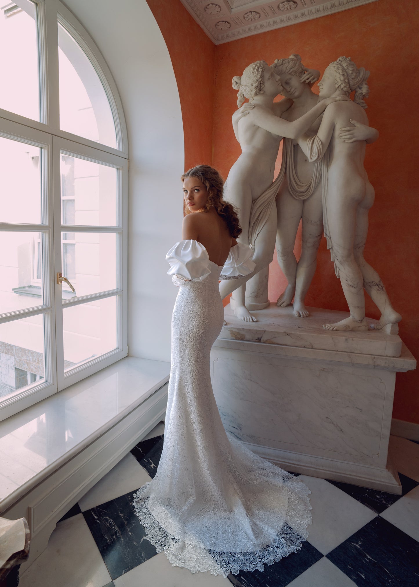 Off-shoulder lace wedding gown with puffed sleeves and fitted silhouette.