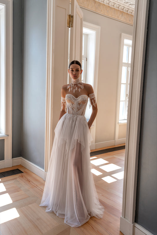 Light boho wedding dress with off-the-shoulder straps, feather detailing, and a lace-up back.