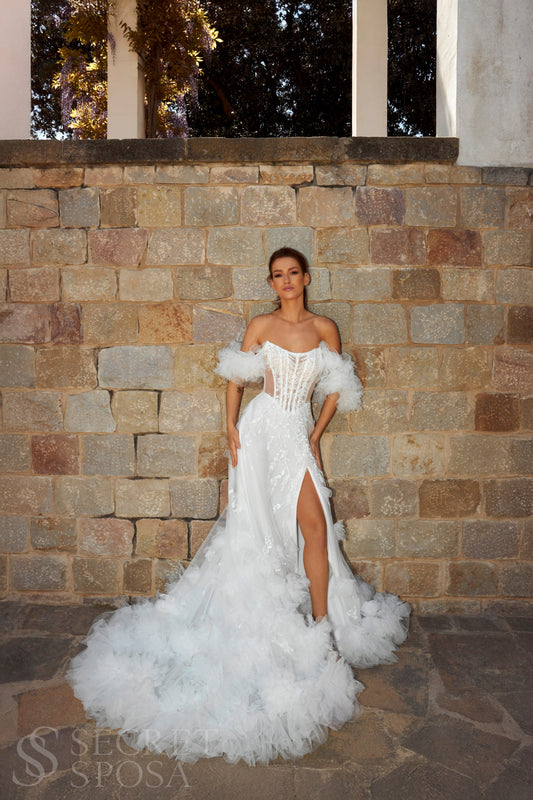 Bride in sleeveless tulle A-line wedding gown with pearl-adorned lace, 3D floral appliqués, boat neckline, slit skirt, drop waist, and straight open back.

