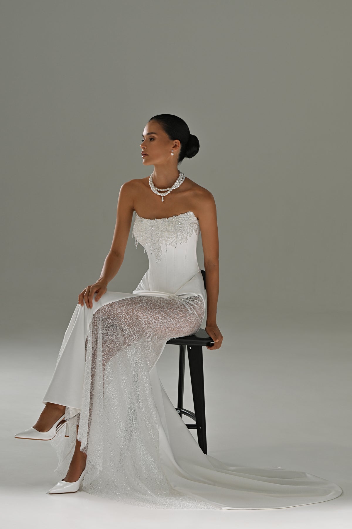 Satin mermaid wedding dress with lace side panels – model seated on a stool showing the lace panel